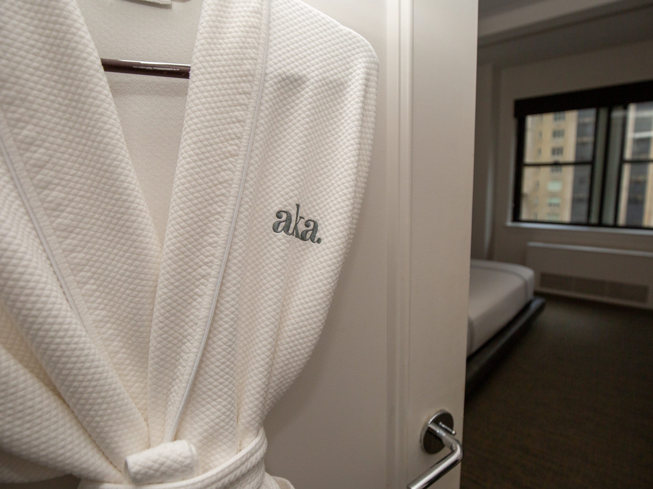 A robe with the "aka" logo hanging on a door.